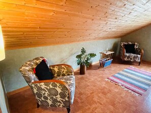 A cozy attic room with two patterned armchairs, a small table, a potted plant, and a colorful striped rug. - 4 Person Holiday Home in Skruv (Skruv)