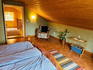 A cozy attic bedroom with a bed, a chair, a small table, and a potted plant. - 4 Person Holiday Home in Skruv (Skruv)