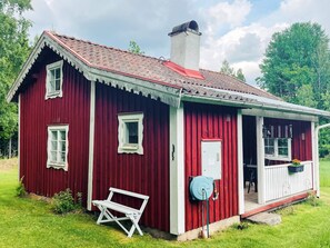 A red wooden house with a white porch, a bench, and a water pump. - 4 Person Holiday Home in Skruv (Skruv)