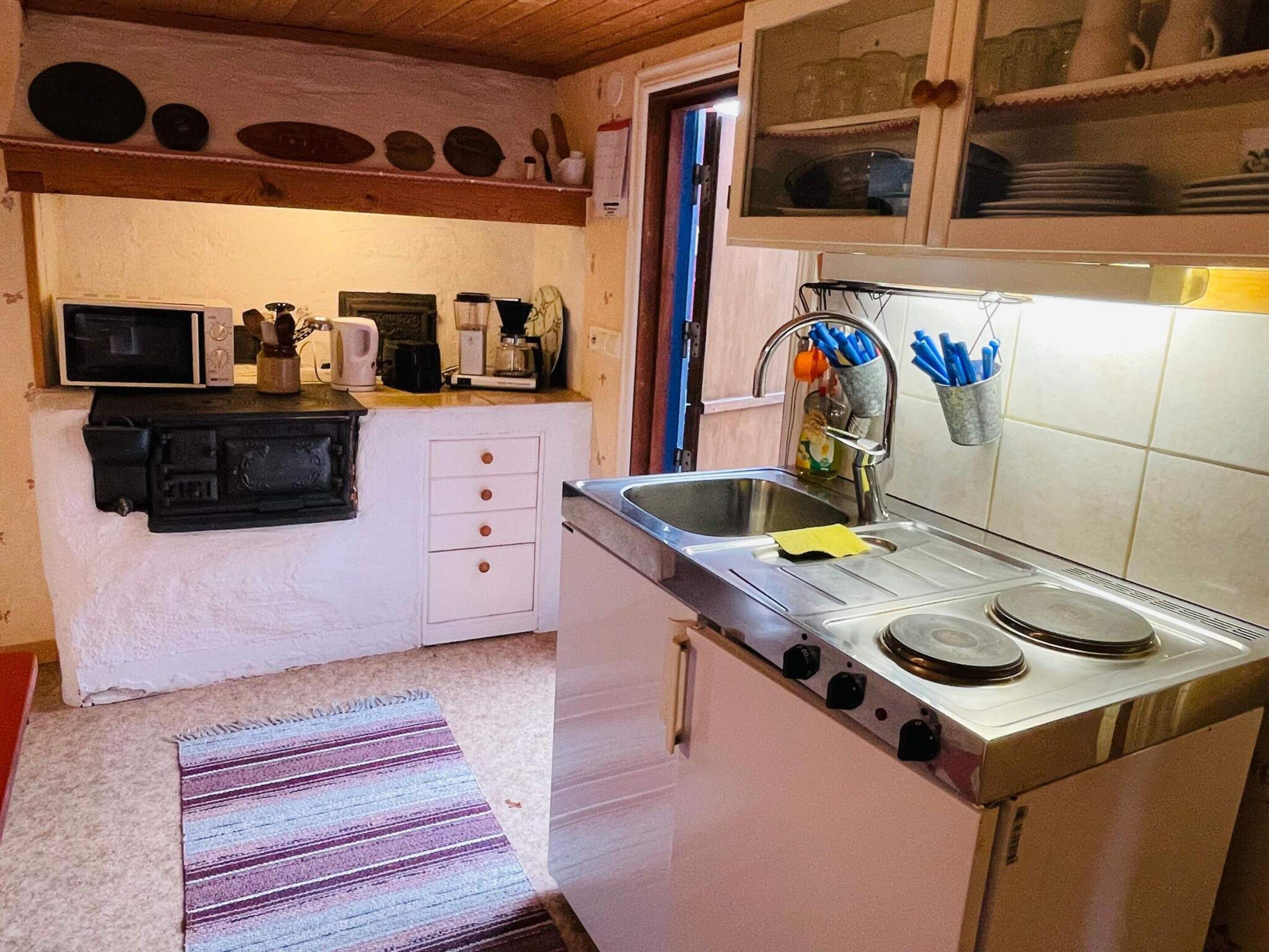 A compact kitchen with a stove, sink, and cabinets.
