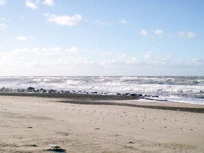 Ein Strand mit brechenden Wellen, die auf eine felsige Küste treffen.