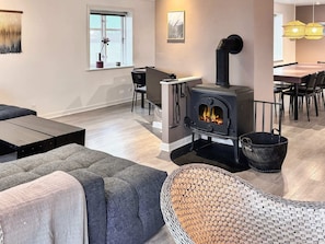 Una sala de estar moderna con chimenea de leña, comedor y un amplio ventanal con vistas.
