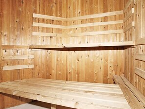A wooden sauna with benches and a slanted ceiling.