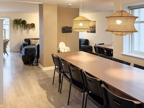 A modern dining area with a long table, black chairs, and hanging lamps. - 4 Star Holiday Home in Harboore (Harboore)