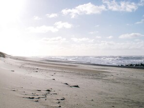 A beach with a wide sandy shore and waves in the background.