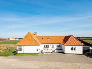 A two-story building with a red-tiled roof, white walls, and a gravel driveway.