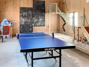 Una mesa de ping pong con ruedas, una pizarra con inscripciones y una pared de madera.