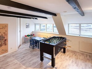 Ein Zimmer mit einem Kicker, Holzböden, einem Fenster mit Blick und einer Heizung.