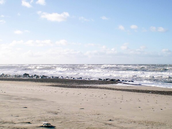 A beach with waves crashing onto a rocky shore.