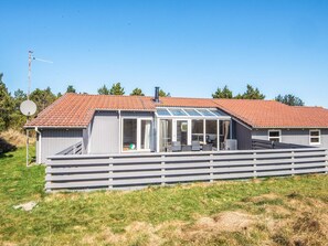 A single-story house with a red-tiled roof, a covered patio area, and a fenced yard. - 10 Person Holiday Home in Blavand (Blavand)