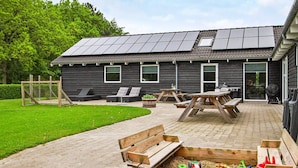 A building with a patio area, outdoor seating, and a children's play area with toys. - 5 Star Holiday Home in Ebeltoft (Ebeltoft)