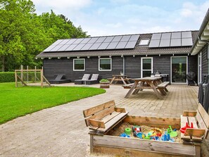 A building with a patio area, outdoor seating, and a children's play area with toys.