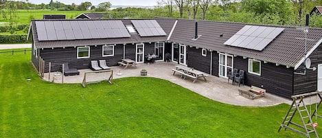 A modern building with a patio area, outdoor seating, and solar panels on the roof.