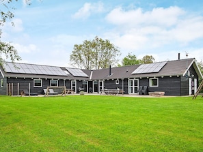 A two-story building with a flat roof, solar panels, and a grassy yard.