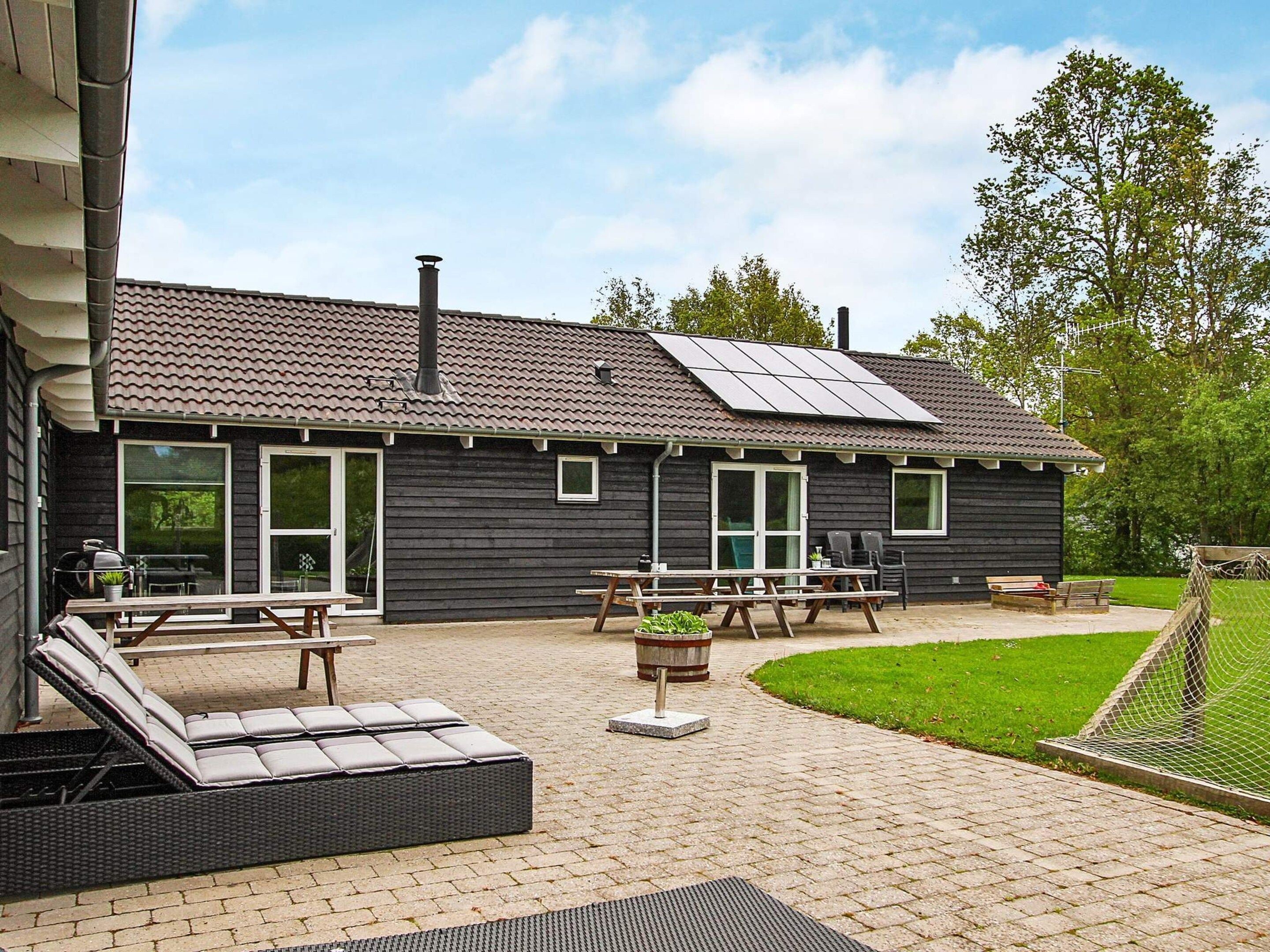 A building with a tiled roof, a chimney, and a patio area with outdoor furniture.