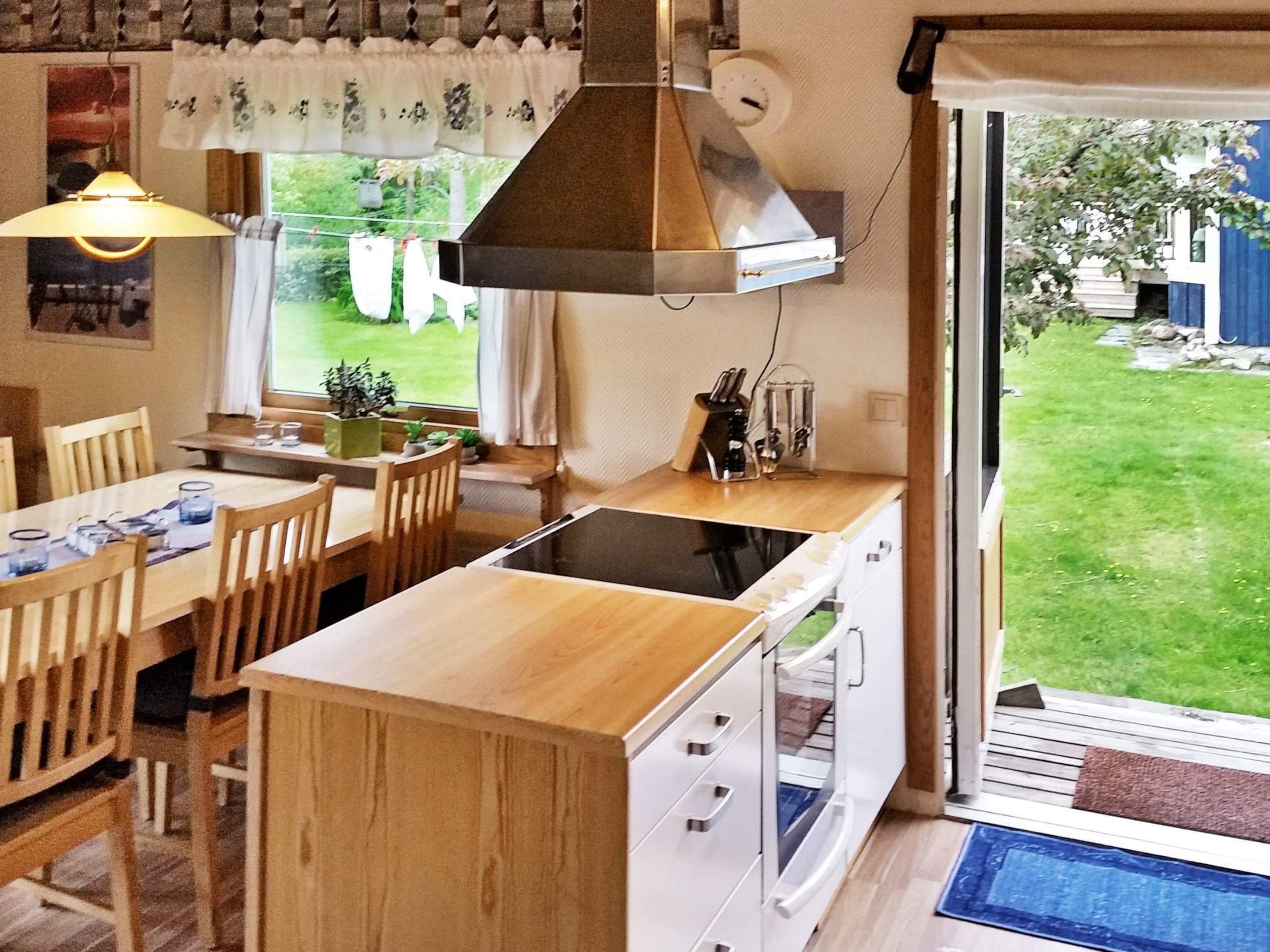 Une cuisine compacte avec un coin repas, des meubles en bois et une vue sur le jardin.