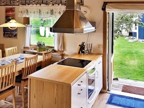 A compact kitchen with a dining area, wooden furniture, and a view of the garden. - Holiday Home in SpekerÃ¶d (Spekeröd)