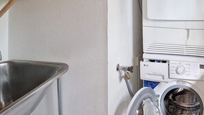 A laundry area with a washing machine, a metal sink, and a shelf with items. - Holiday Home in SpekerÃ¶d (Spekeröd)