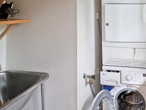 A laundry area with a washing machine, a metal sink, and a shelf with items. - Holiday Home in SpekerÃ¶d (Spekeröd)