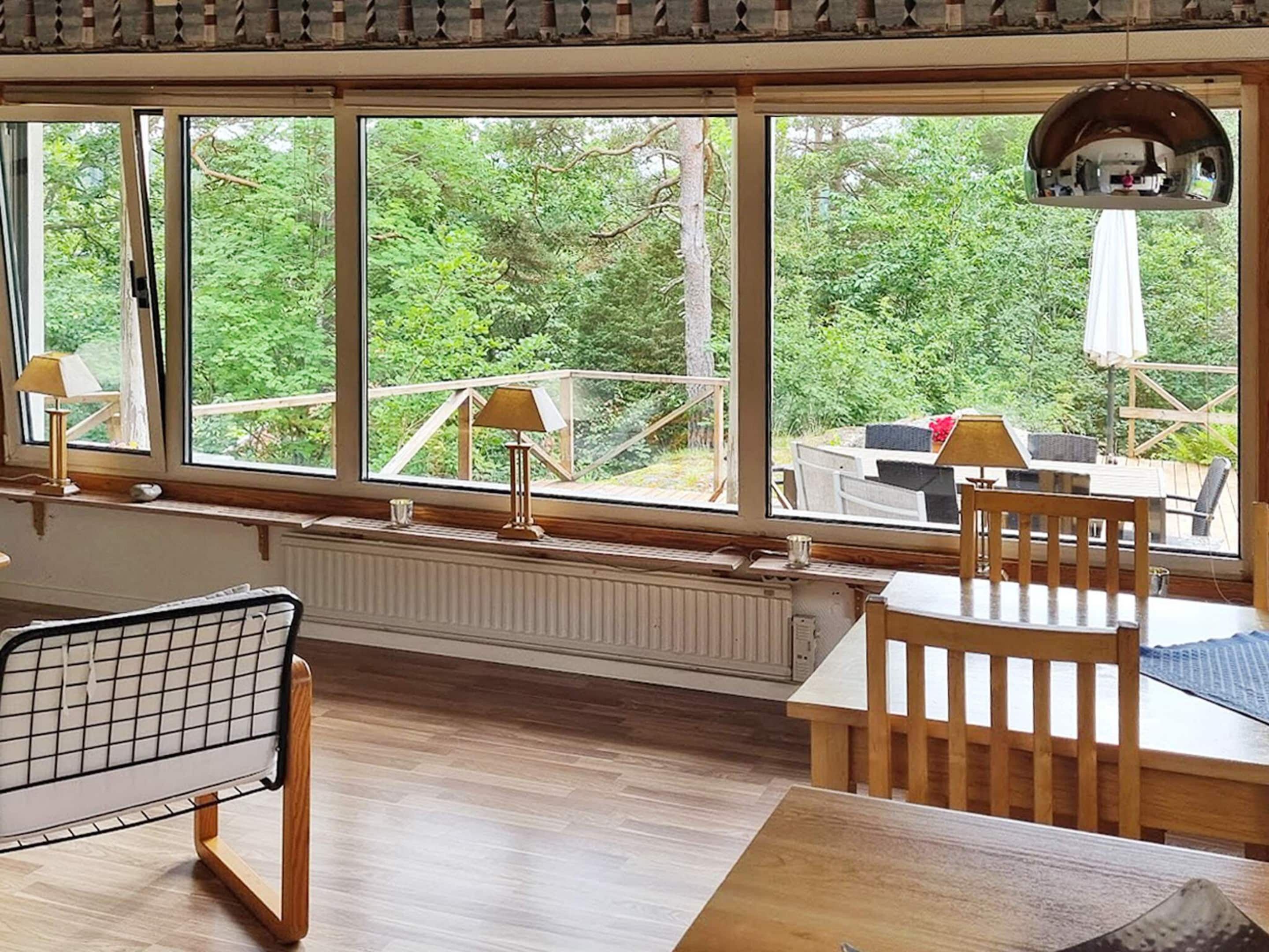 Una habitación con ventanas amplias, un radiador, una mesa y una silla.