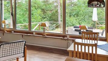 Una habitación con ventanas amplias, un radiador, una mesa y una silla.