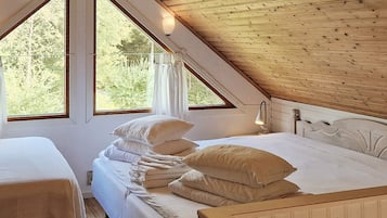 Une chambre avec un plafond en pente, deux lits et de grandes fenêtres.