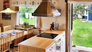 A kitchen with a wooden island, white cabinets, and a window overlooking a garden. - Holiday Home in SpekerÃ¶d (Spekeröd)