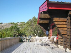 A wooden deck with outdoor furniture, a red roofed structure, and a natural backdrop. - Holiday Home in HÃ¤lleviksstrand (Hälleviksstrand)