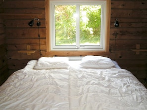 A room with a bed, a window, and two wall-mounted lamps. - Holiday Home in HÃ¤lleviksstrand (Hälleviksstrand)