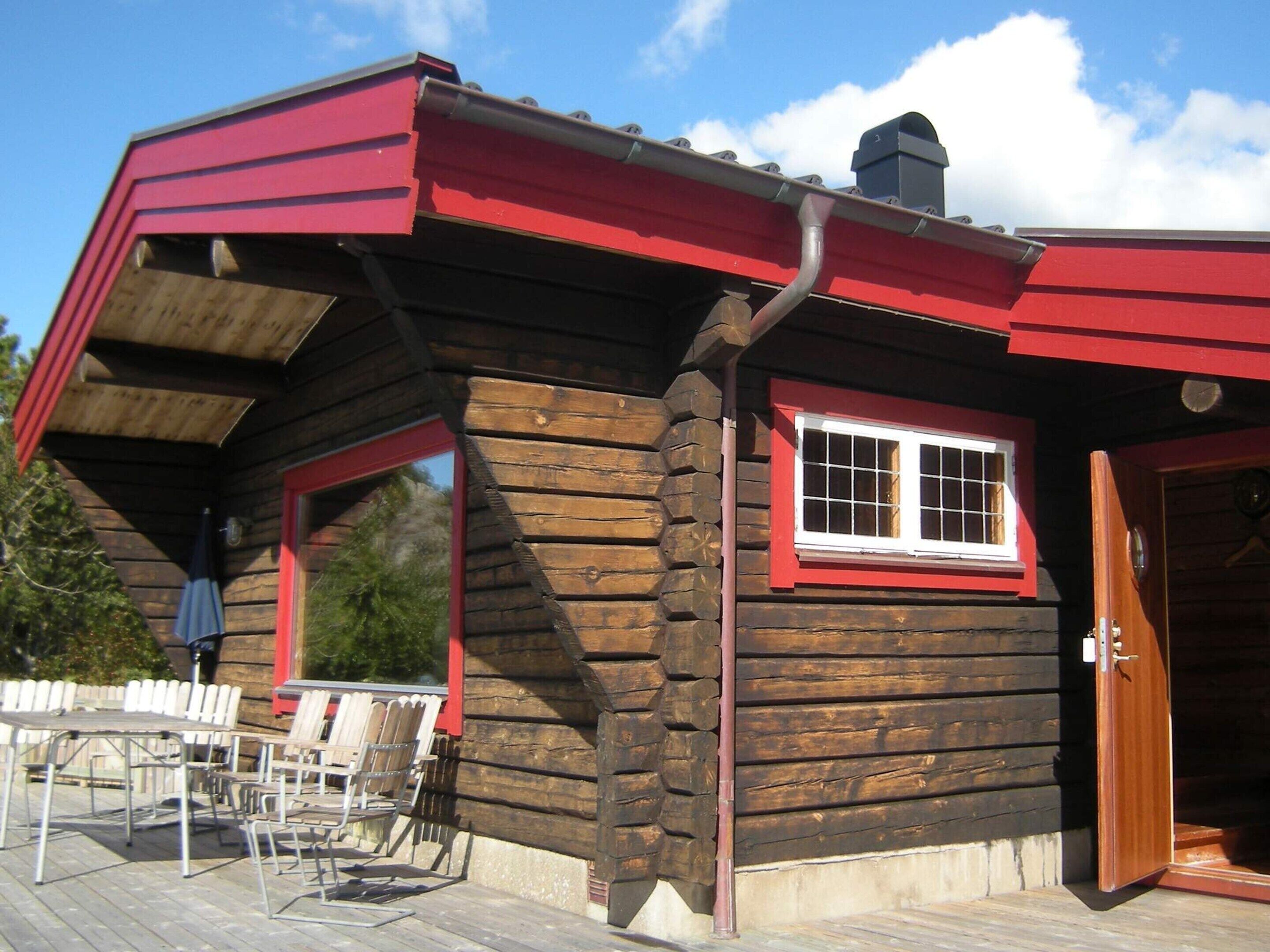 A wooden cabin with a red roof, a window with white trim, and a door.