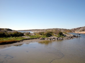 Paisatge natural amb un riu, terreny roc ós i una petita construcció de fusta.