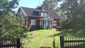 A two-story house with a porch, a chimney, and a fenced yard.