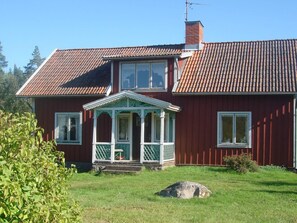 A two-story red house with a tiled roof, a porch with white trim, and a chimney. - 6 Person Holiday Home in Morlunda (Mörlunda)