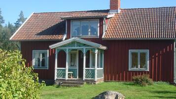 A two-story house with a red exterior, a tiled roof, and a small porch with white trim.