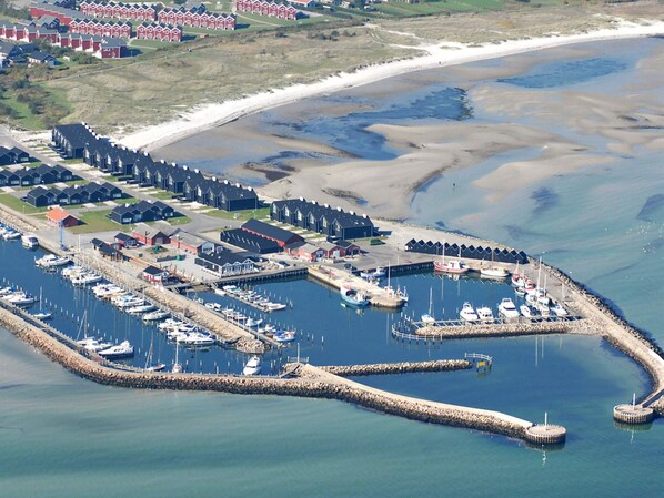 An aerial view of a coastal marina with boats docked, a pier, and a row of houses in the background. - Spacious Villa near Beach in Hadsund (Hadsund)