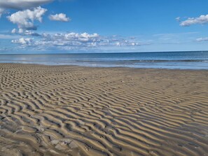 A sandy beach with gentle waves and a clear sky.