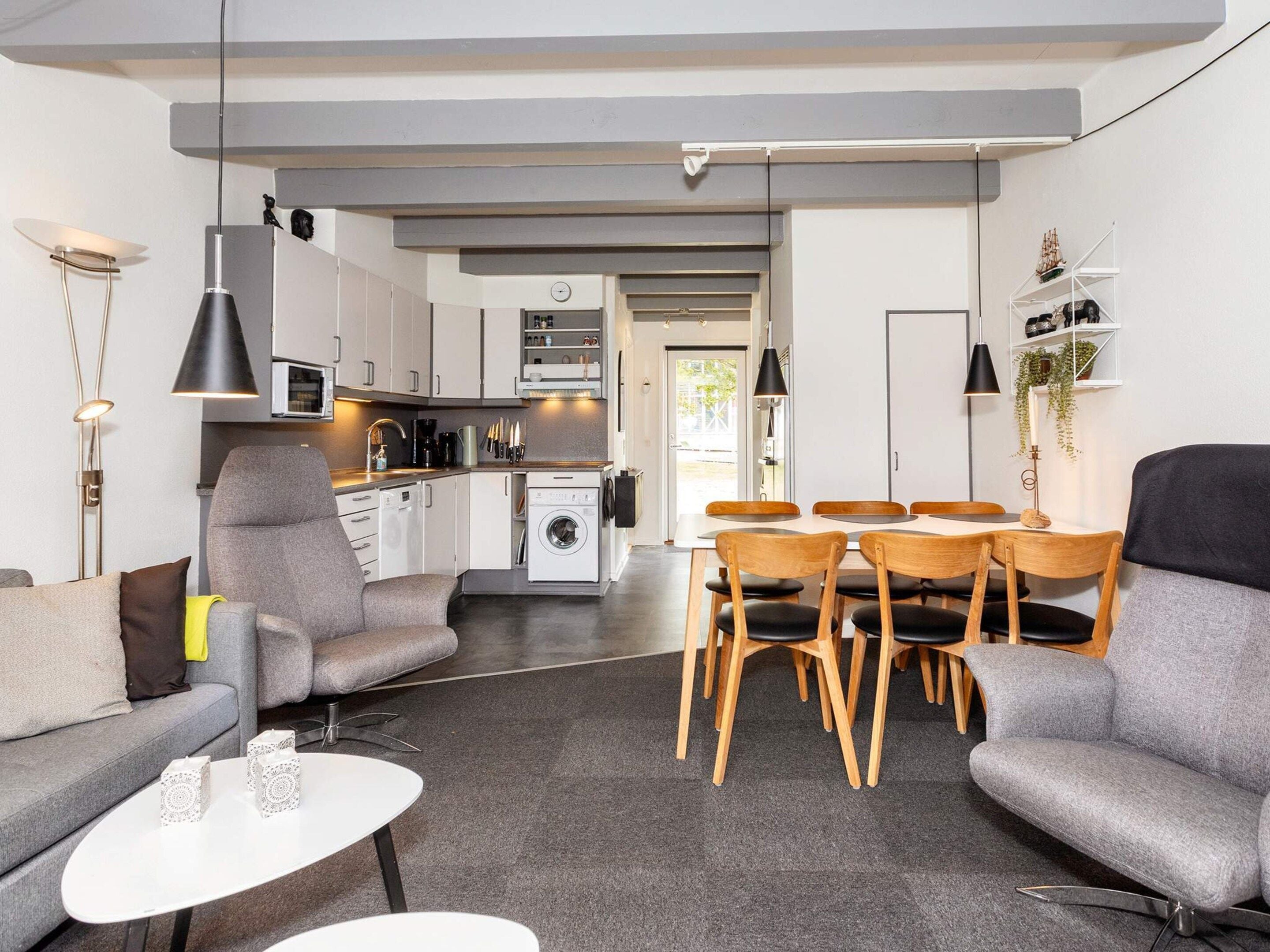 Un soggiorno moderno con un divano, un tavolino da caffè e un'area pranzo con sedie in legno.
