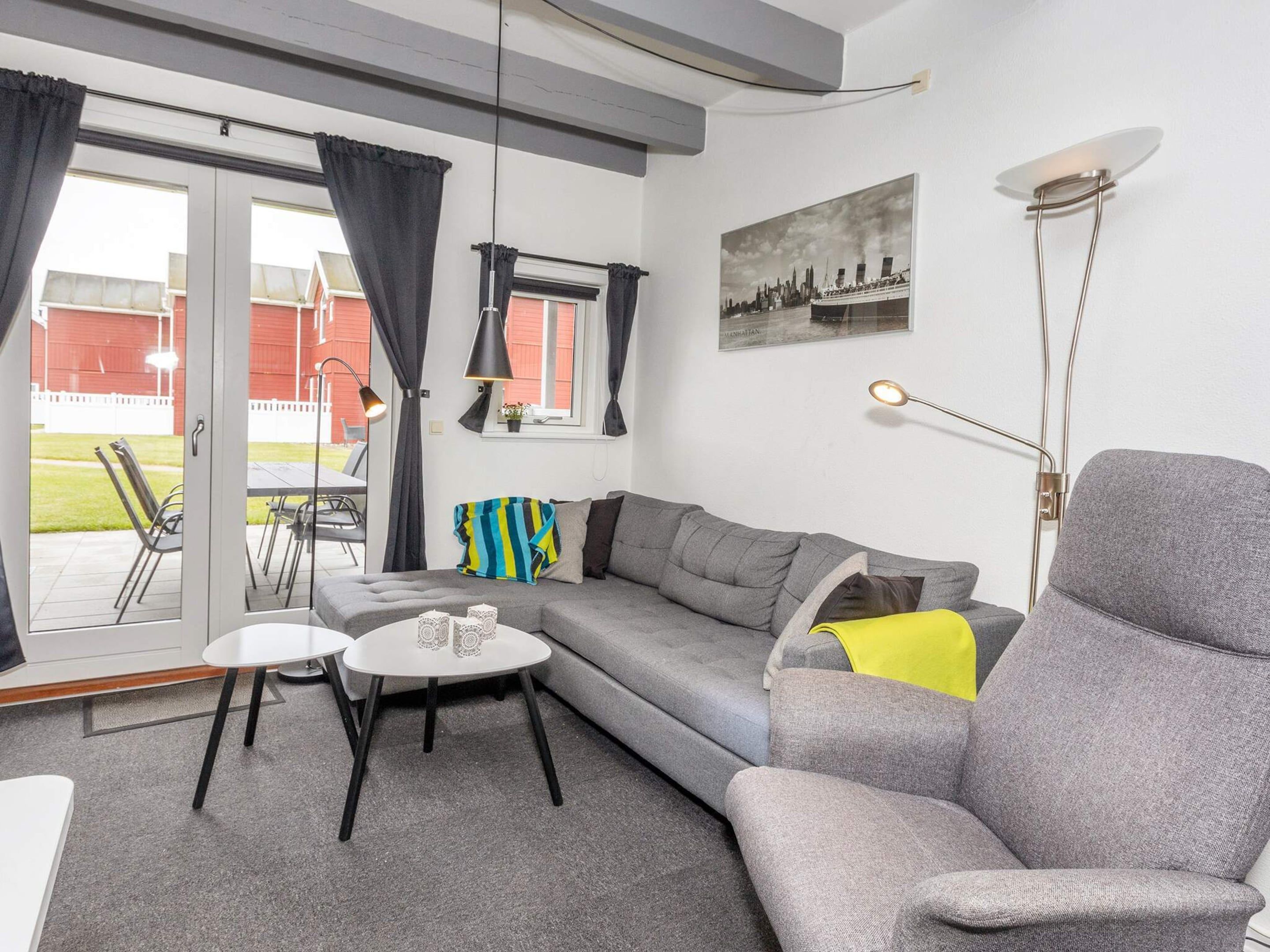 Un salon moderne avec un canapé gris, une petite table blanche et un lampadaire.