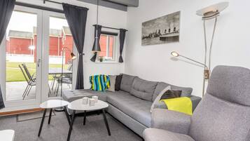 A modern living room with a grey sofa, a small white table, and a floor lamp.