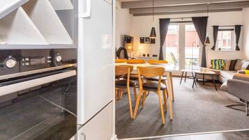 A modern kitchen with a built-in oven and a dining area with wooden chairs and a table.