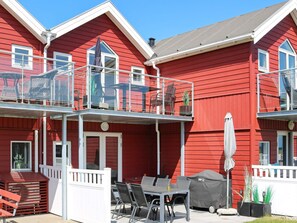 A red building with a balcony, outdoor seating, and a grill.