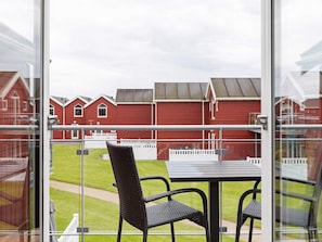 A balcony with a table and chairs, overlooking a row of red buildings with white fences. - Spacious Villa near Beach in Hadsund (Hadsund)
