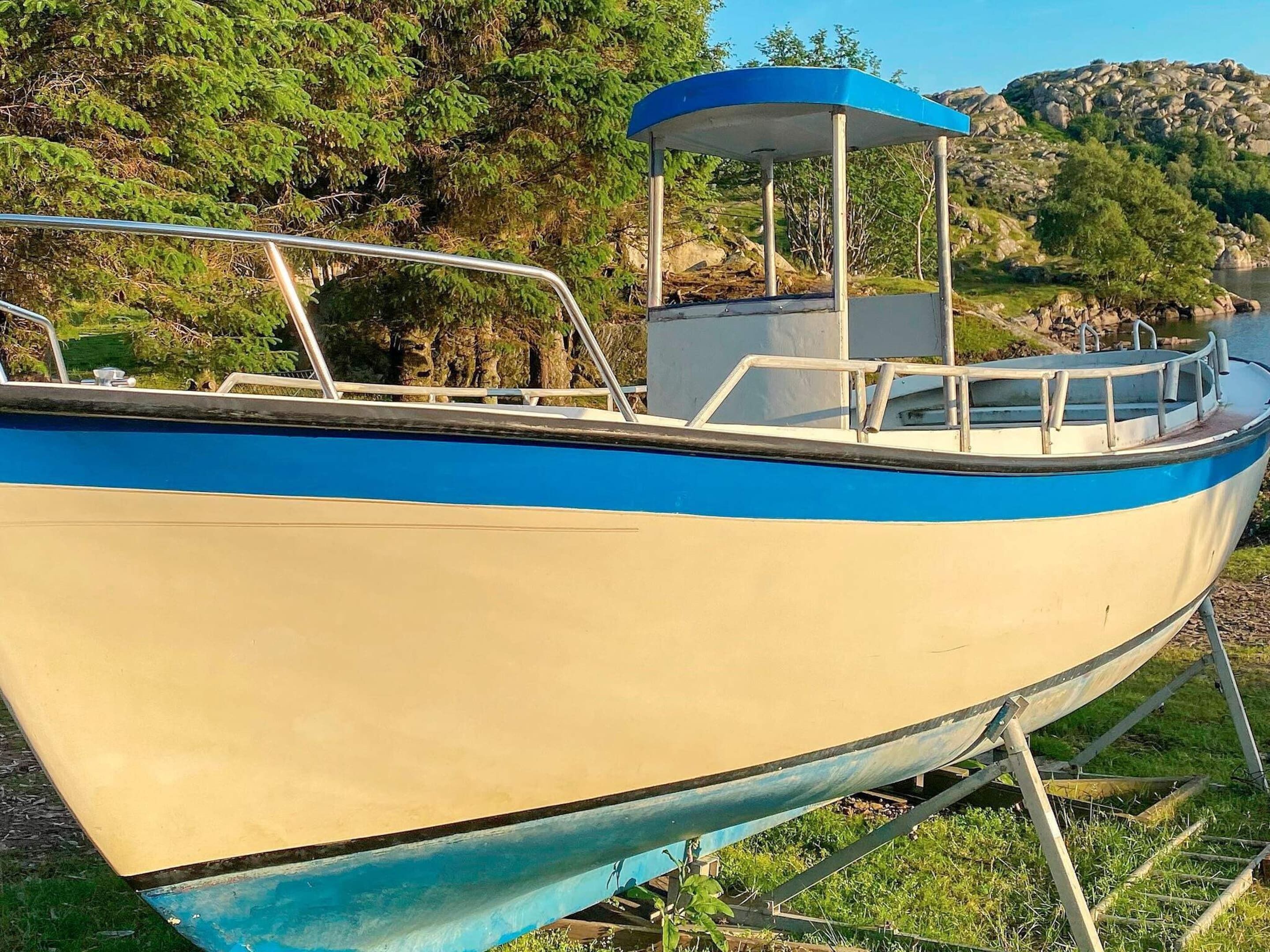 A boat with a blue and white hull, a covered seating area, and metal railings.