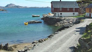 A coastal road leading to a red and white house with a dock extending into the water. - 6 Person Holiday Home in Ballstad-by Traum (Vestvågøy)