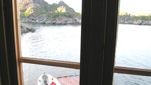 A view of a small boat docked at a pier with rocky hills in the background. - 6 Person Holiday Home in Ballstad-by Traum (Vestvågøy)