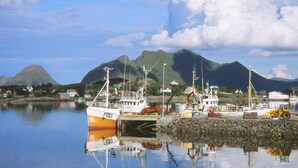 A harbor with boats, a tractor, and a mountain in the background. - 6 Person Holiday Home in Ballstad-by Traum (Vestvågøy)