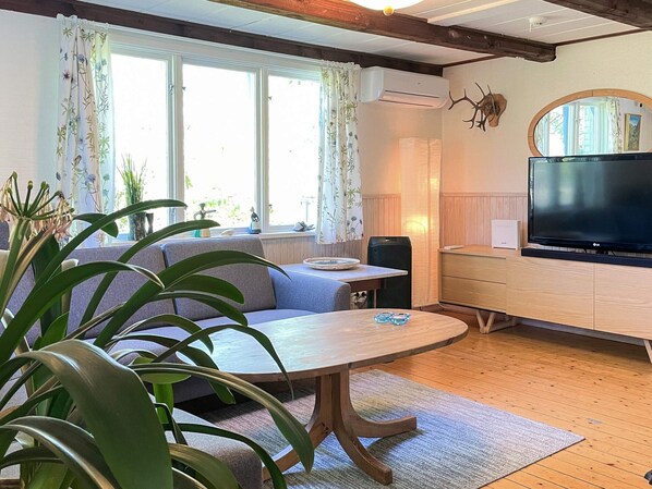 A cozy living room with a wooden table, a sofa, and a television. - 4 Person Holiday Home in Klippan (Klippan)