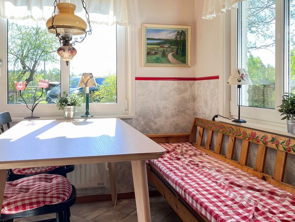 Ett rum med en träbänk, ett bord och en tavla på väggen.