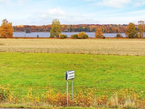 A sign in a grassy field with a lake and autumn trees in the background. - 5 Person Holiday Home in Lonashult (Lönashult)