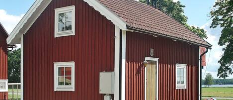 A red wooden building with a gabled roof, a small porch, and a single door.